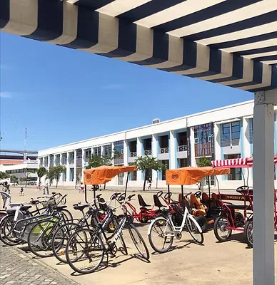 Bicicletas e triciclos de aluguer estacionados sob a pérgola às riscas