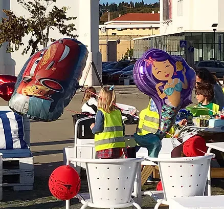 Mesa de festa de aniversário com balões e crianças de colete reflector