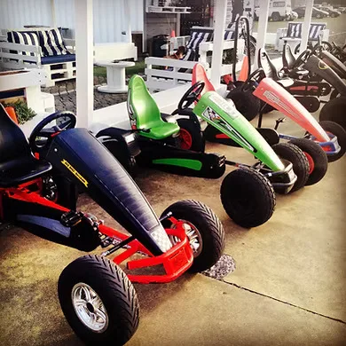 Karts a pedal de várias cores alinhados sob a cobertura